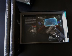 Et blik ned i æsken, mens bøgerne står på højkant. Alskens fine bilag til at understøtte spillet.